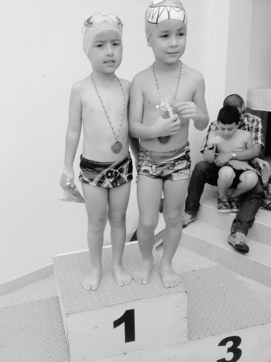Dos niños con medallas sobre el podio de una competencia