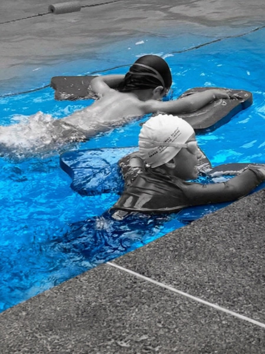 Dos nadadores entrenando con monoaleta y tabla en la piscina