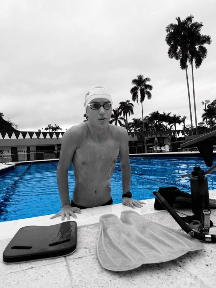 Konsta apoyado en el borde de la piscina junto a la tabla y la monoaleta